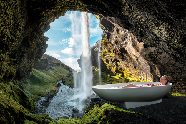 Blick aus einer Höhle hinter einem Wasserfall. Frau badet in Badewanne